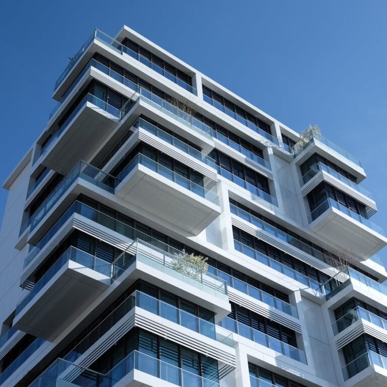 Striking low-angle shot of a modern condominium with unique balcony design and clear blue sky.